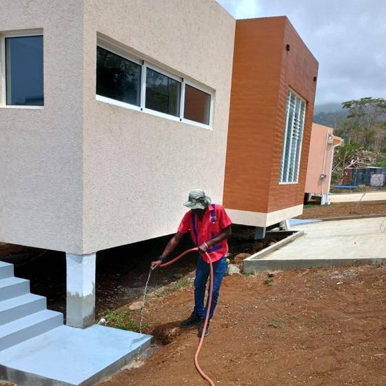 Technician applying termite soil treatment along the foundation of a new build in Grenada